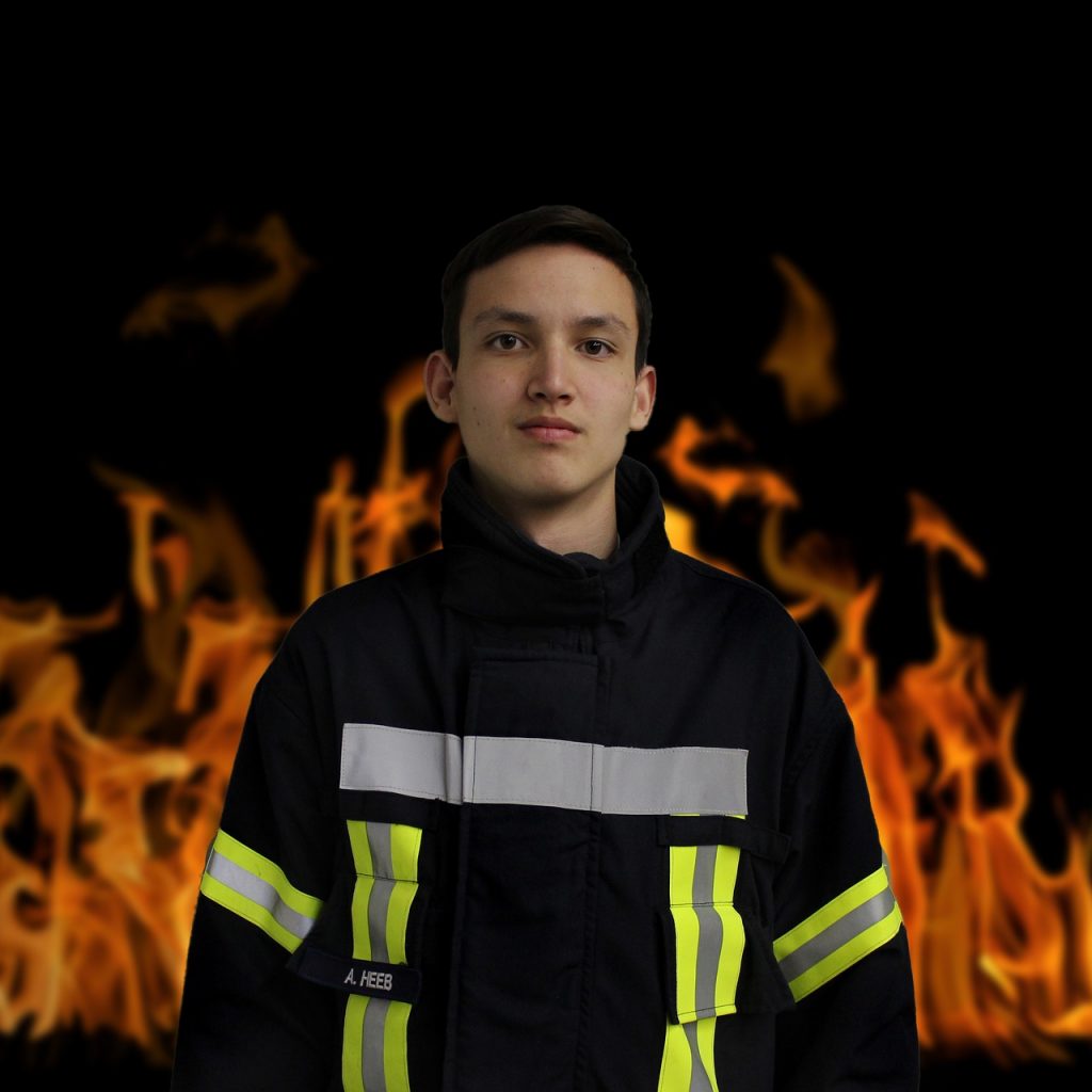 Feuerwehrmann steht vor Flammenhintergrund.
