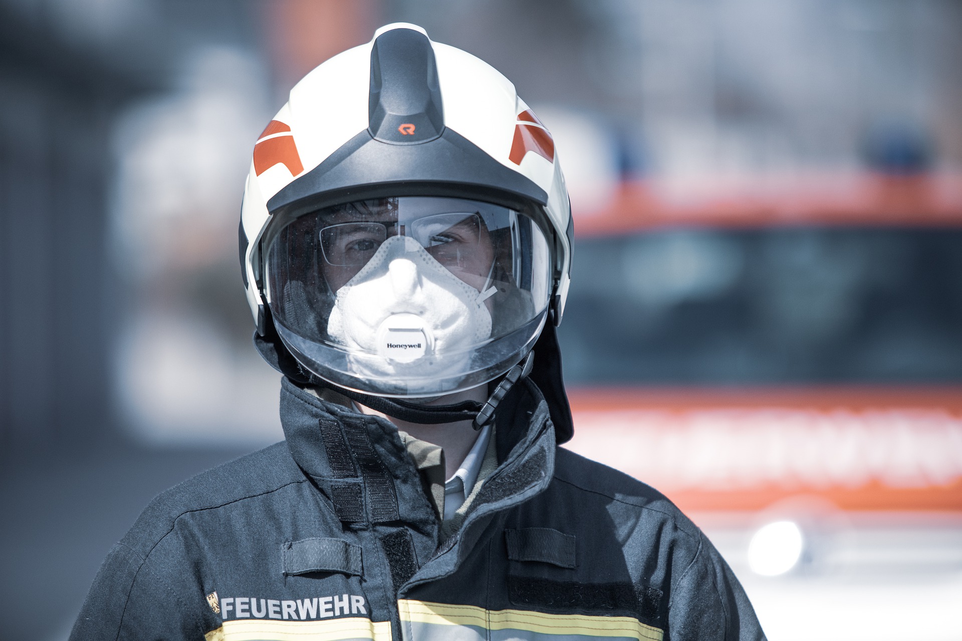 Feuerwehrmann mit Helm und Maske vor Feuerwehrfahrzeug.
