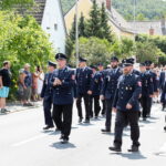 Feuerwehrmarsch durch Dorfstraße mit Zuschauern
